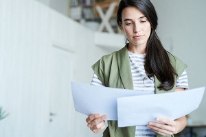 Junge Frau liest in Dokumenten, die sie in der Hand hält